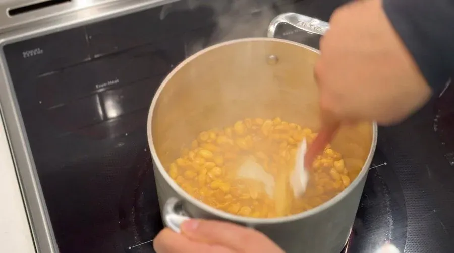 Pot of roasted peanuts with spices being deglazing with water for peanut satay sauce.