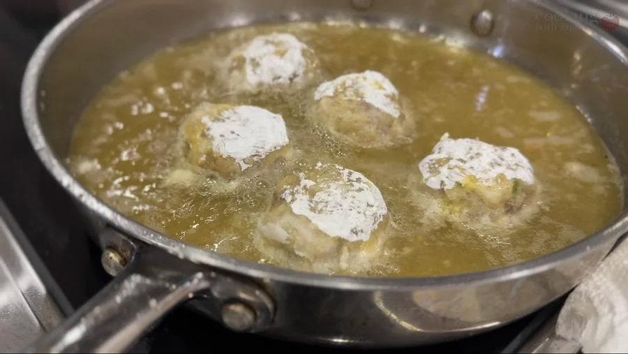 Golden-brown perkedel potato fritters frying in hot oil in a skillet, halfway through cooking.