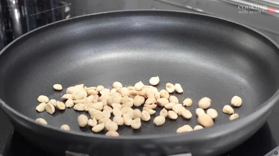Dry roasted peanuts in a dark skillet on stovetop.