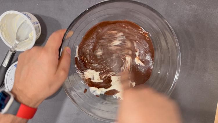 Mixing Nutella and cream cheese together in a glass bowl with a hand mixer.