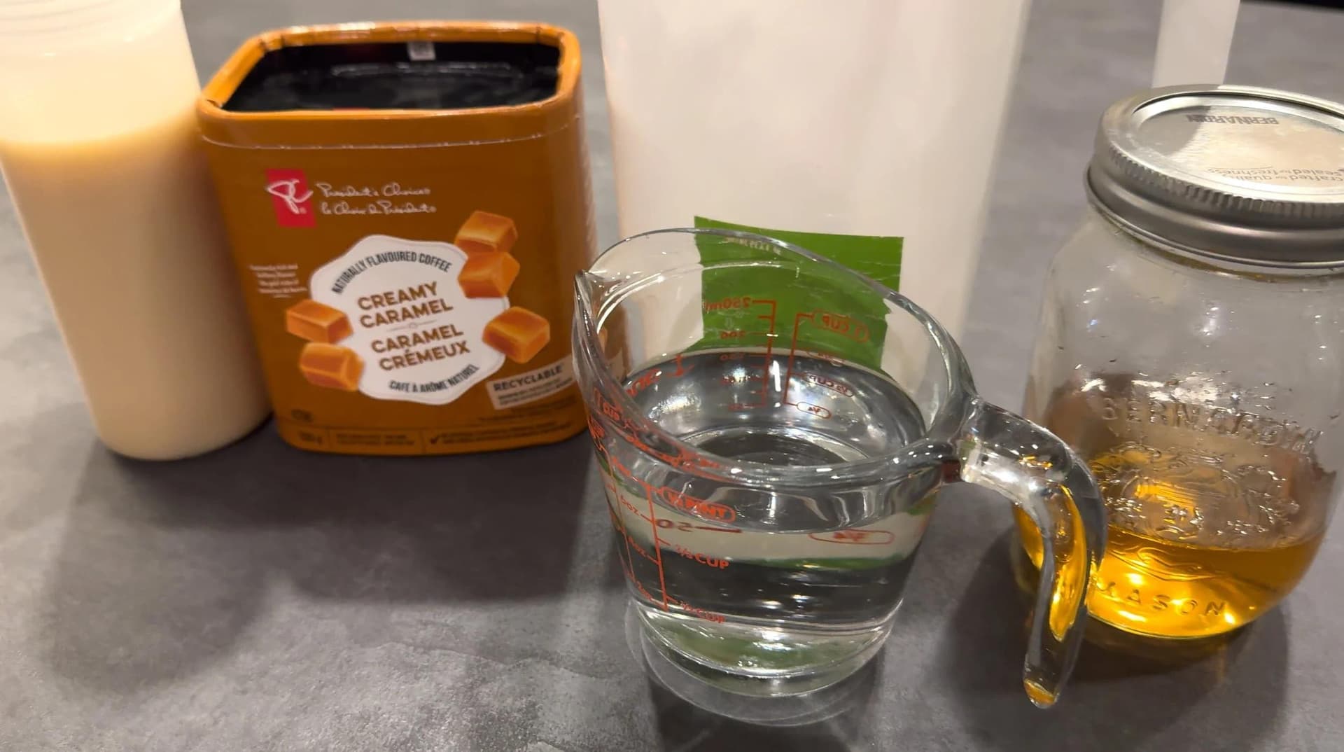Ingredients for homemade caramel macchiato: creamy caramel sauce, water, and heavy cream in glasses.