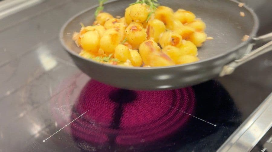 Baby potatoes sautéed in butter and herbs in a skillet, golden brown with herbs visible on top.