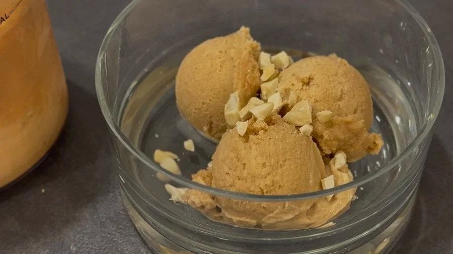 High protein ginger chai ice cream scoops in a glass bowl garnished with chopped cashew nuts