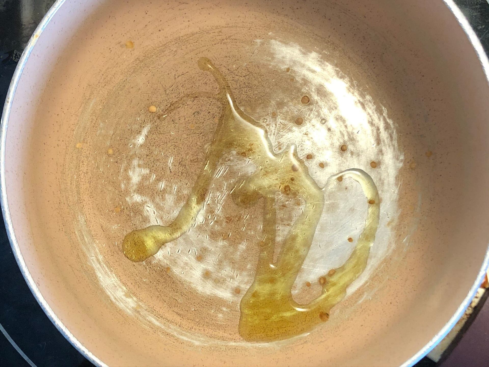Olive oil pooling in a ceramic pot on the stove, ready for sautéing ingredients.