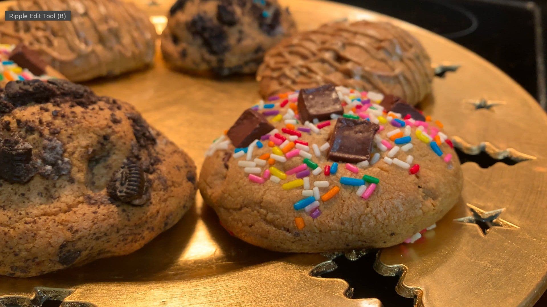 Stuffed cookies on a gold surface decorated with colorful sprinkles, chocolate chunks, and black star decorations.