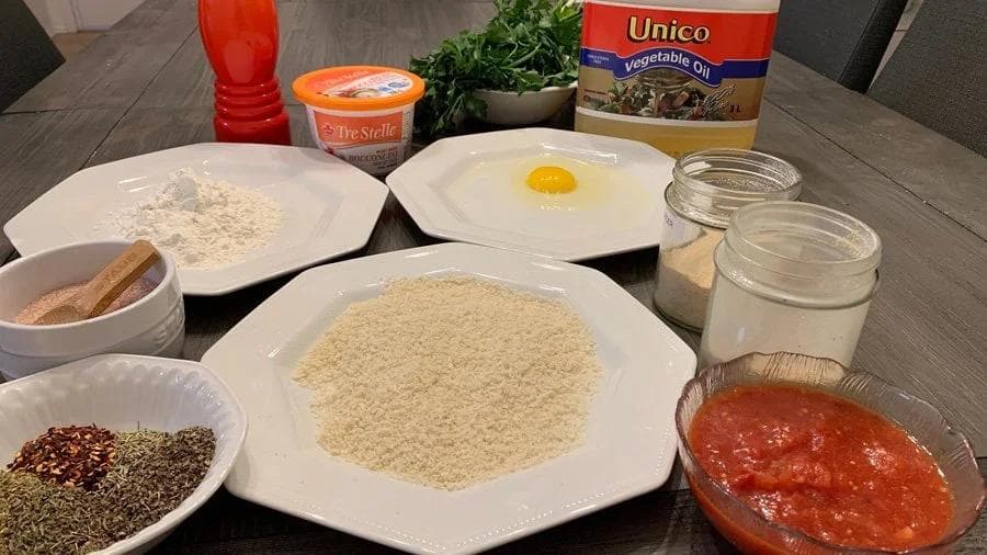 Ingredients laid out for crispy mozzarella balls including flour, breadcrumbs, egg, tomato sauce, and seasonings.