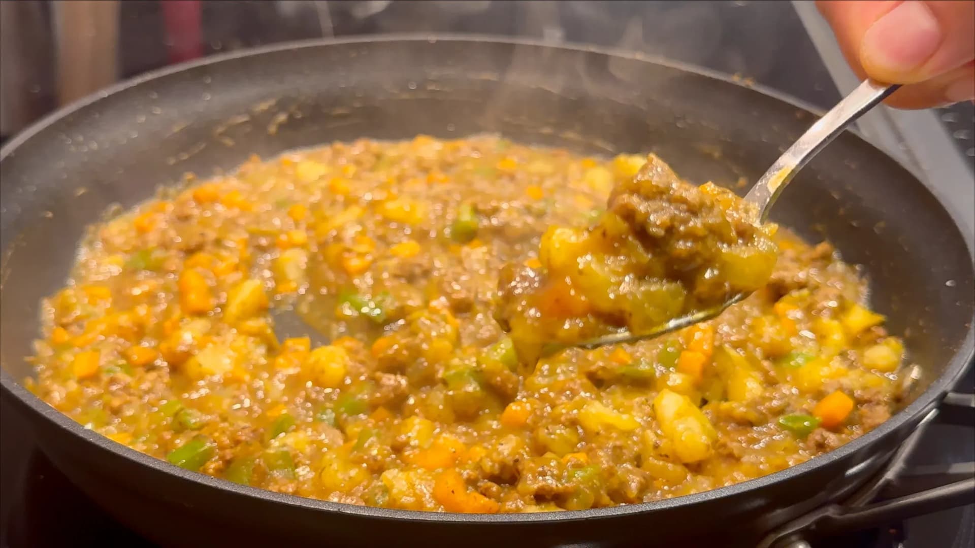 Thick meat filling with vegetables and ground meat in a pan, being stirred with a spoon, showing the thickened gravy consistency.