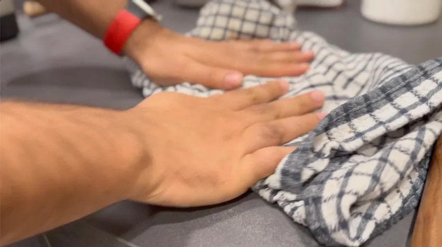 Hands rubbing roasted hazelnuts in a kitchen towel to remove the skin.