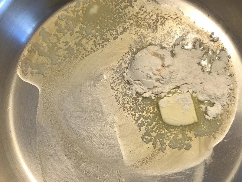 Melted butter and flour cooking together in a stainless steel pan to form a roux for béchamel sauce.