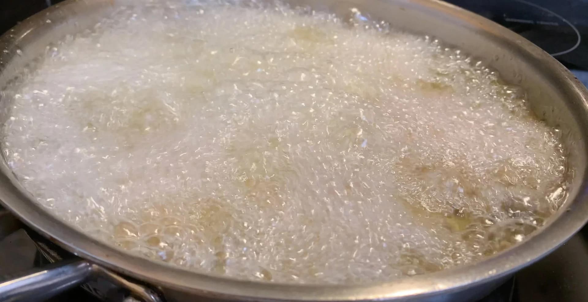 Oil heating in a pan on medium heat for frying potato patties until golden brown.