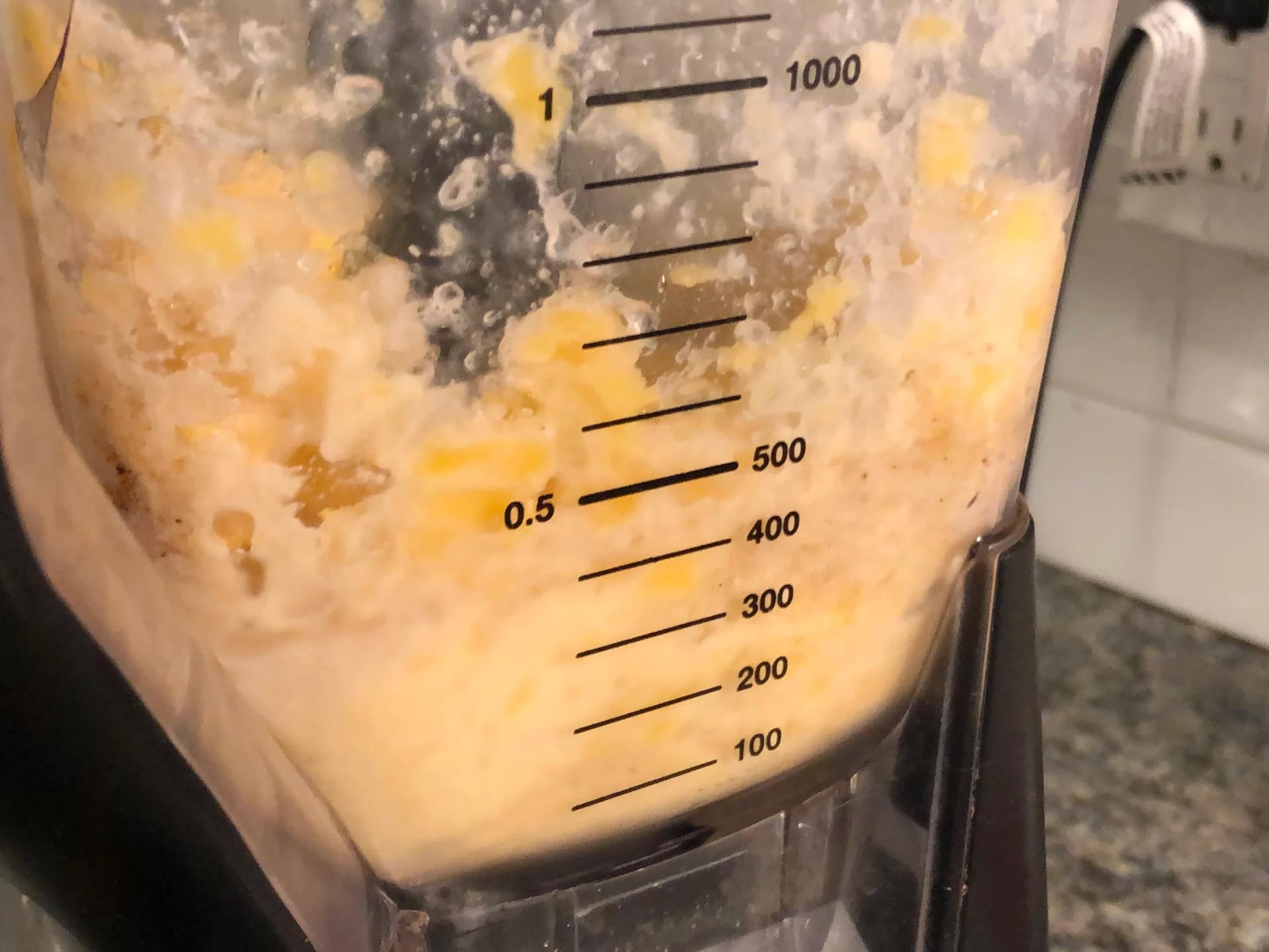 Blender filled with creamy mango protein ice cream mixture being blended until smooth.