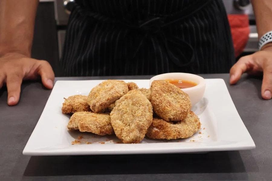 Golden-brown air fryer chicken nuggets on a white plate with dipping sauce