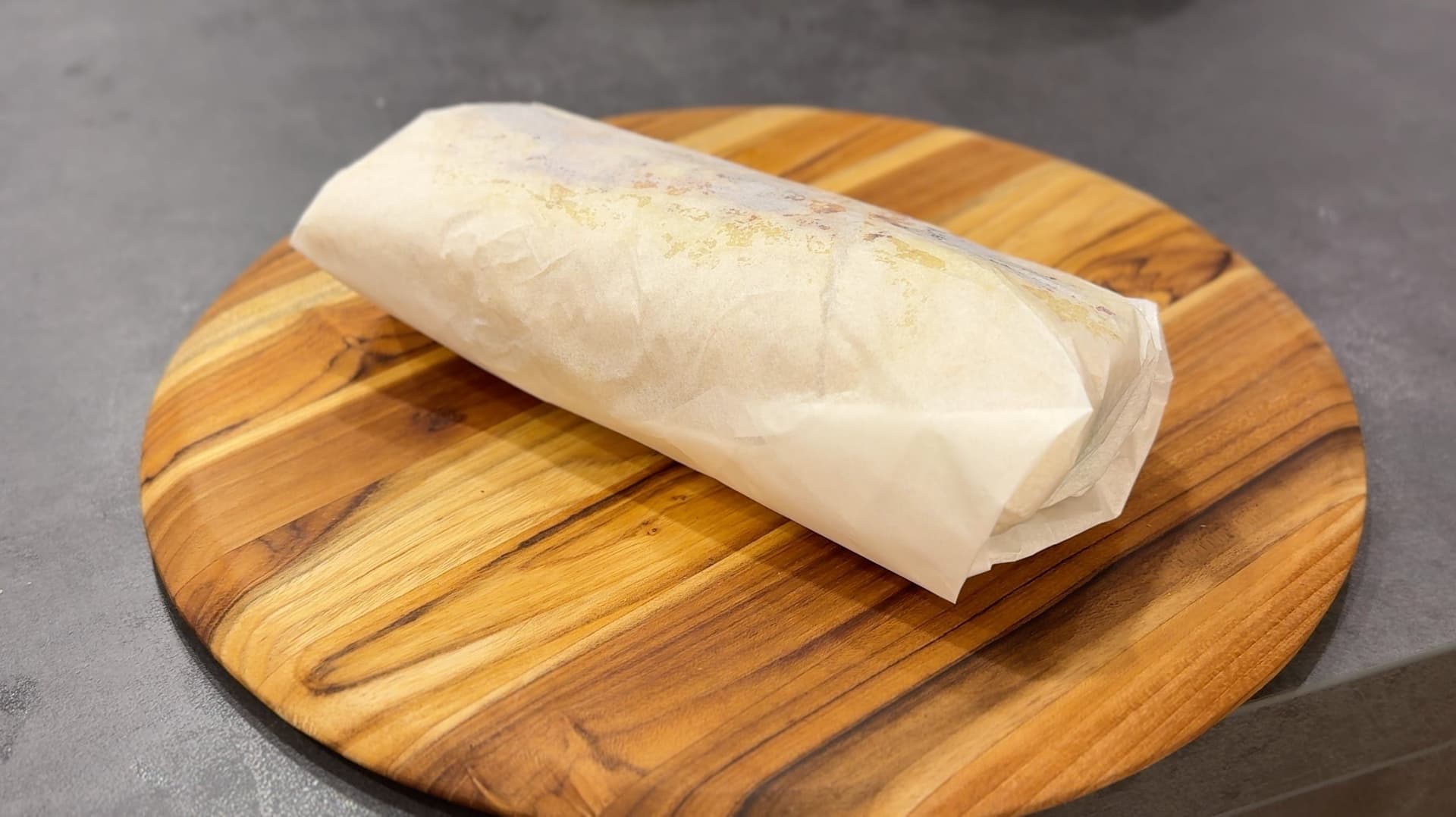 Chicken shawarma sandwich wrapped in parchment paper on a wooden board, ready to serve.