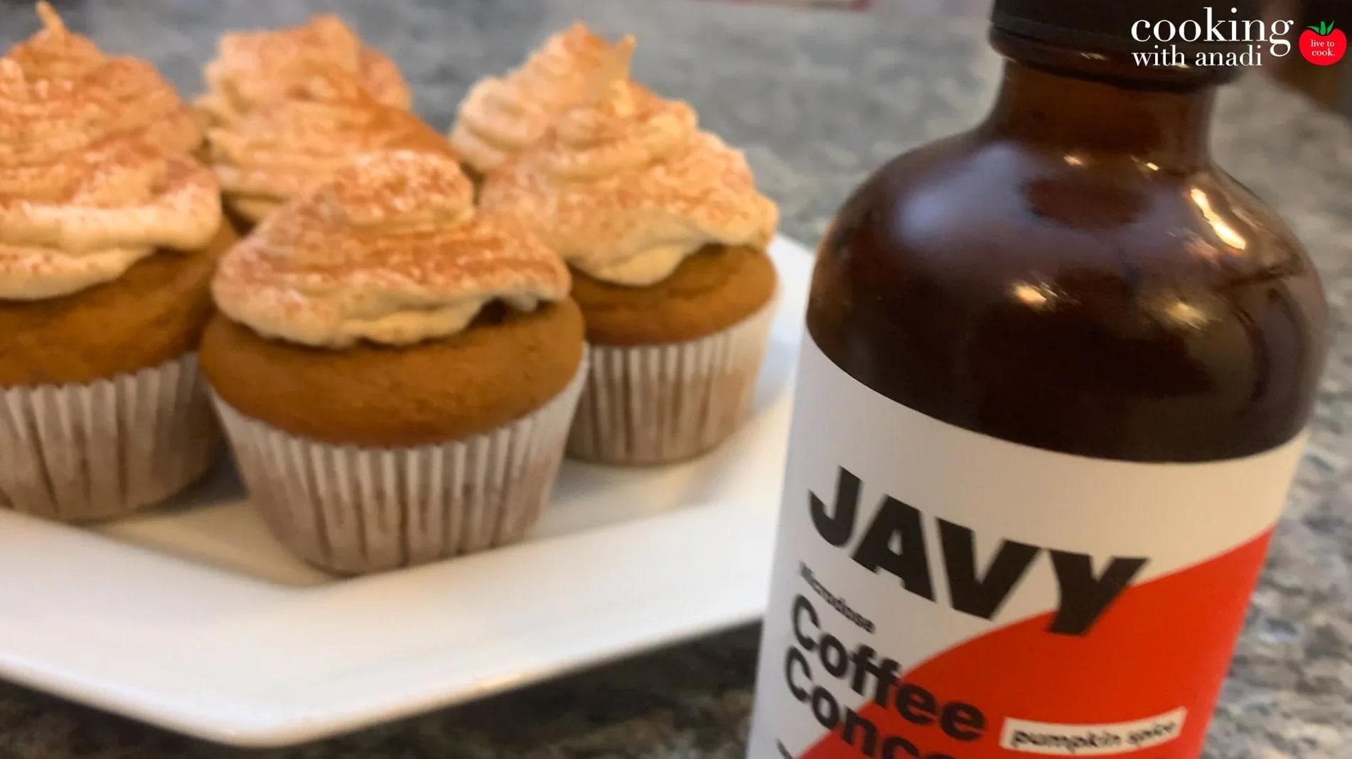 Pumpkin spice latte cupcakes with cinnamon frosting next to a bottle of Javy Coffee concentrate.