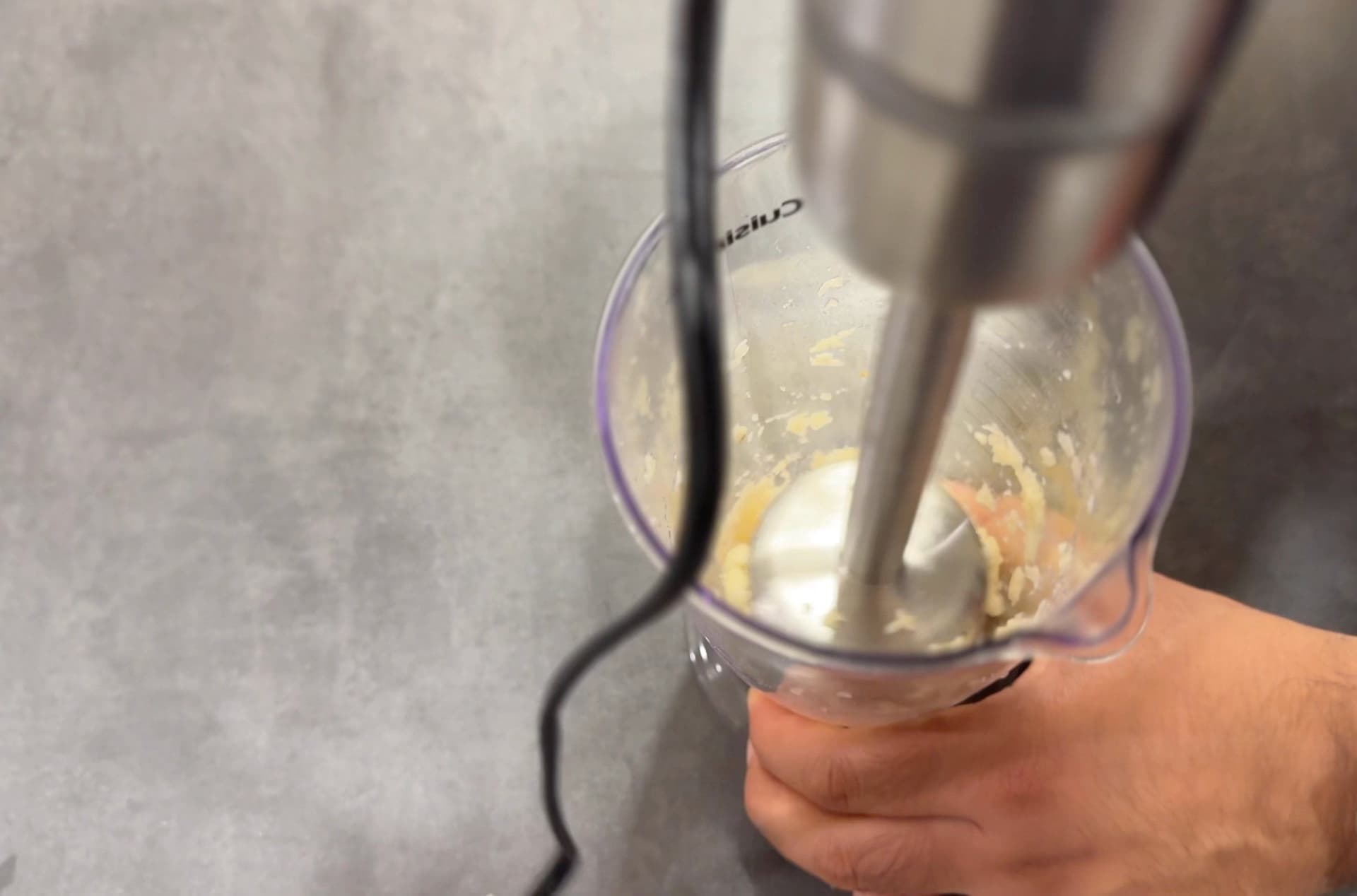 Immersion blender blending garlic puree in a wide-mouth jar while making toum sauce