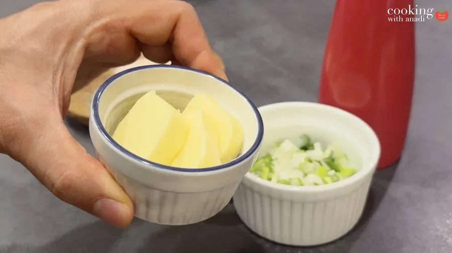 Butter and diced potatoes in small bowls with chopped green onions ready for air fryer cooking.