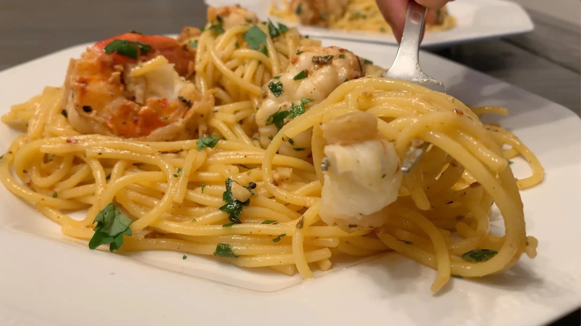 White wine lemon garlic shrimp scampi with spaghetti garnished with fresh parsley on a white plate.