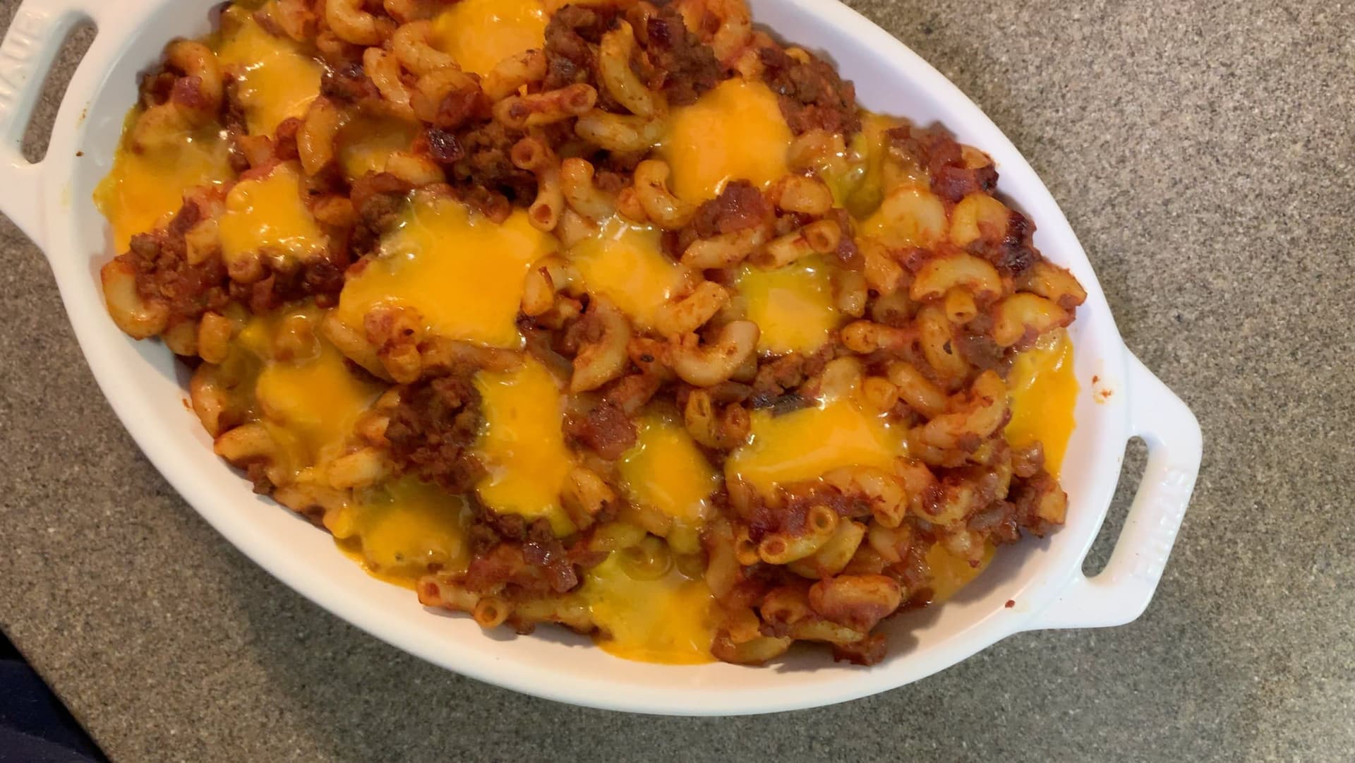 Baked cheeseburger mac and cheese in a white casserole dish with melted cheddar cheese and ground beef.