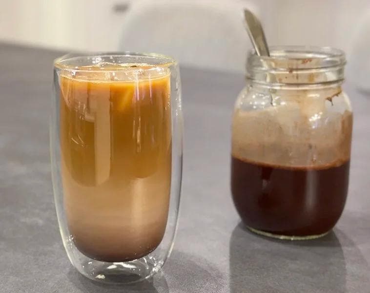 Iced chocolate latte in a double-walled glass next to a jar of concentrated espresso shot.