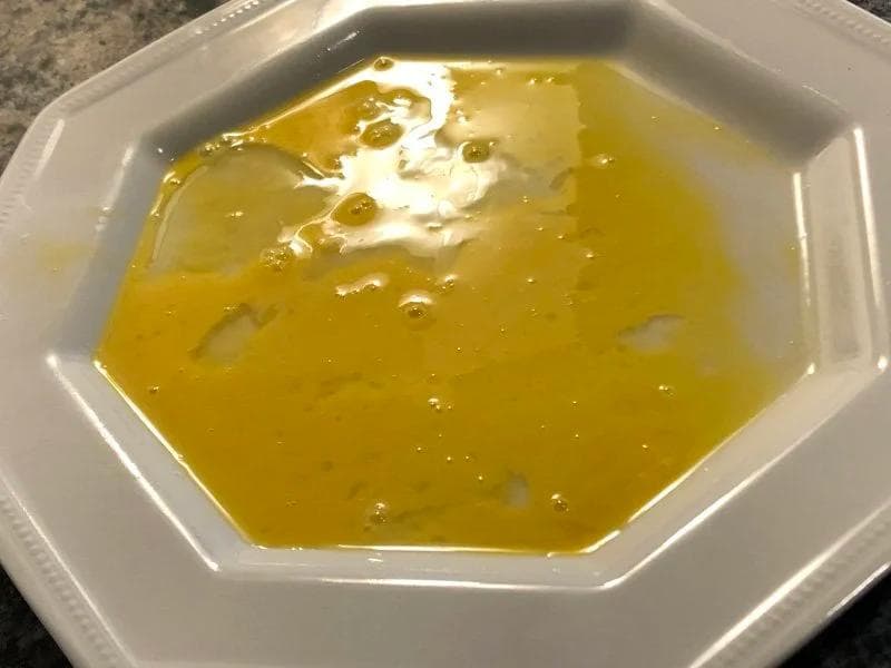 Whisked egg in a white bowl ready for dredging chicken breasts during panko coating preparation.