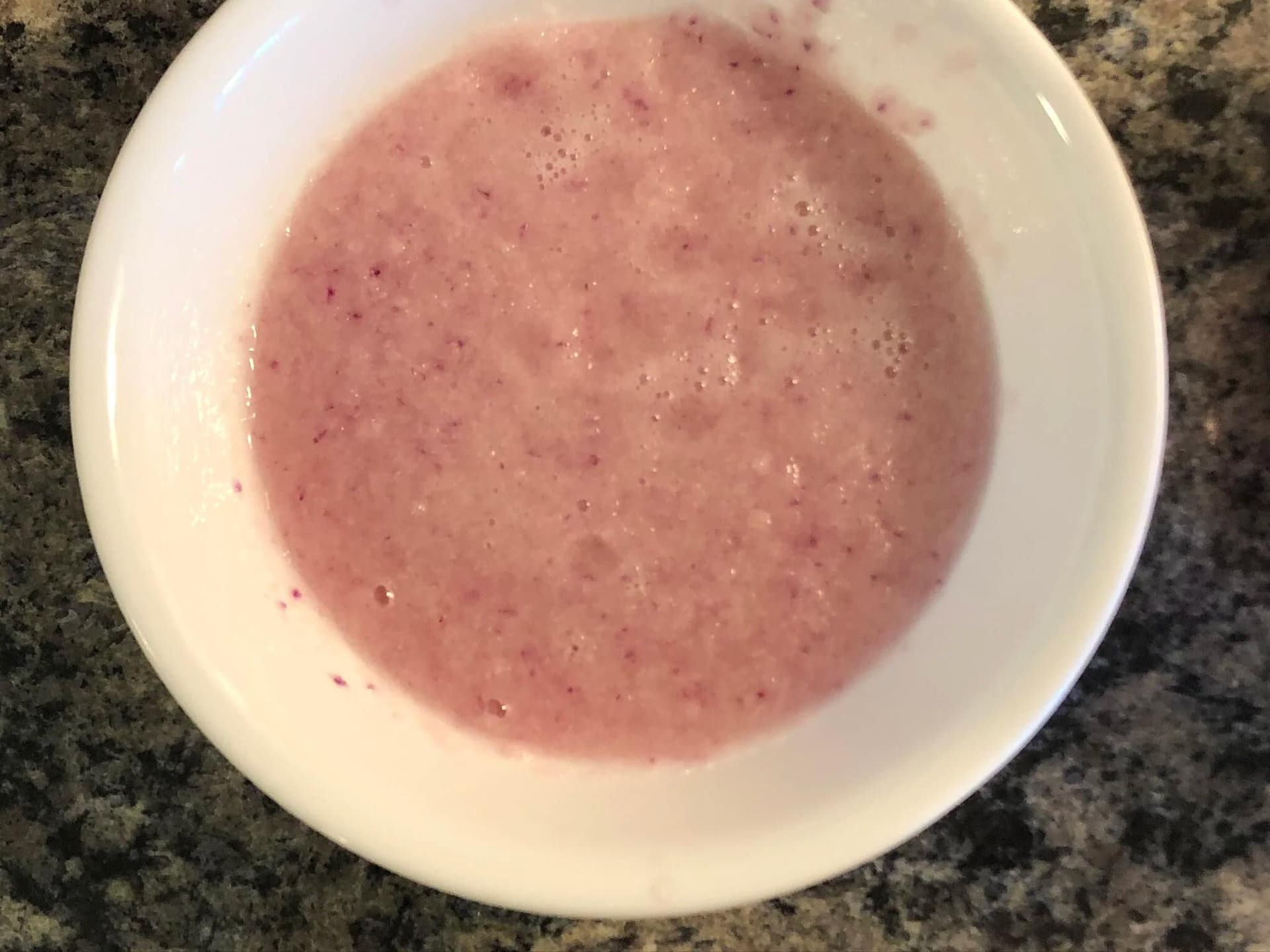 Smooth pink lentil puree in a white bowl on a granite countertop