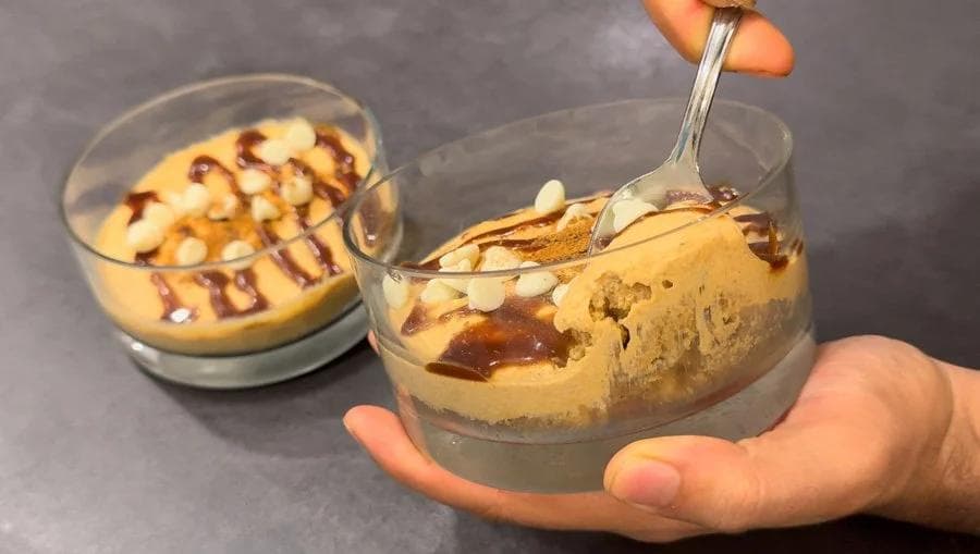 Pumpkin spice no-bake cheesecake in glasses with caramel drizzle and a spoon, showing creamy texture.