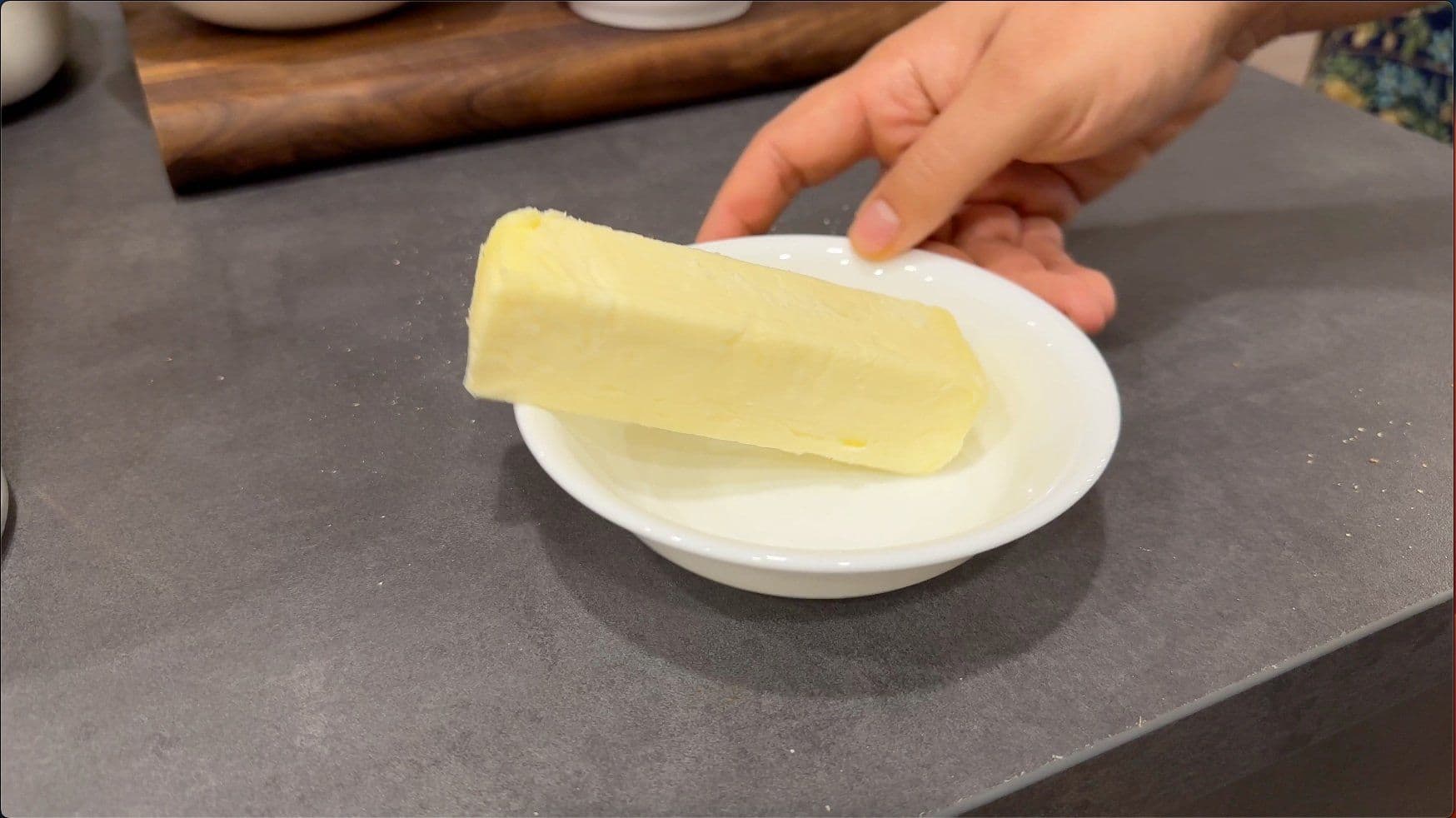 Melted butter and brown sugar mixture being spread on a white plate during French toast casserole preparation.