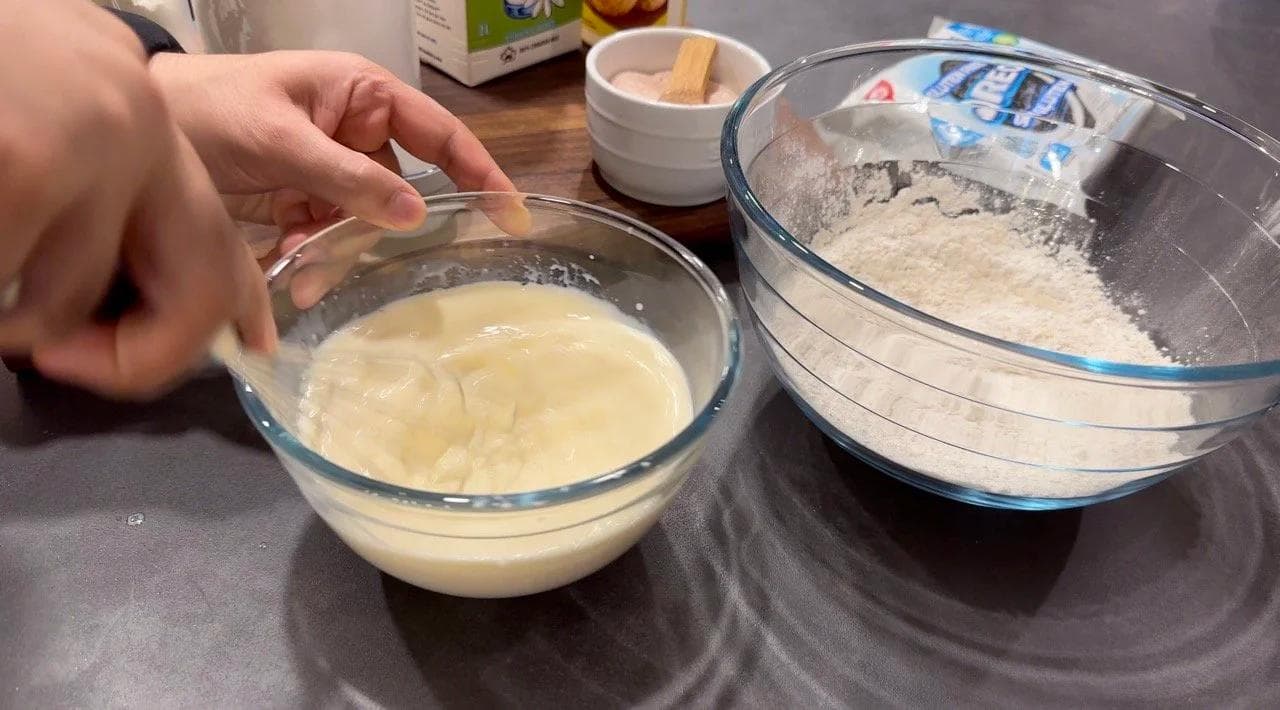 Wet and dry ingredients for gluten-free pancake batter in separate glass bowls on a kitchen counter