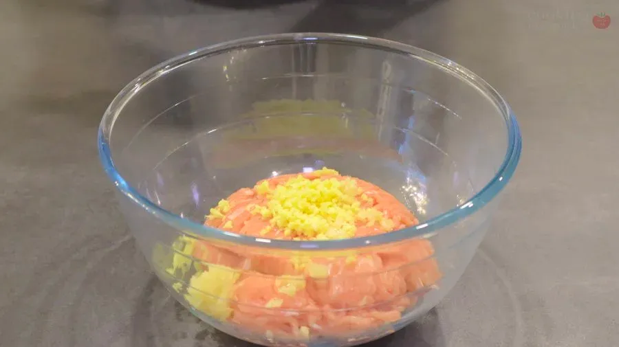 Mixed ground chicken filling with diced carrots and yellow corn in a glass bowl.