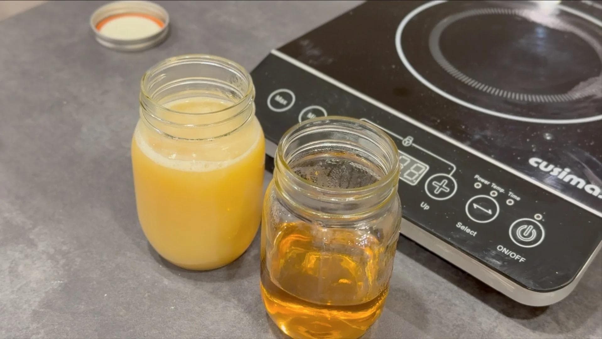 Two glass jars with homemade caramel syrup cooling, alongside a Ninja coffee maker on gray countertop.