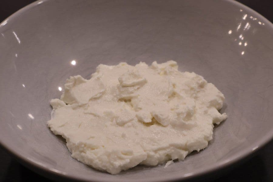 Thick, creamy hung curd with a soft, lumpy texture served in a gray ceramic bowl.