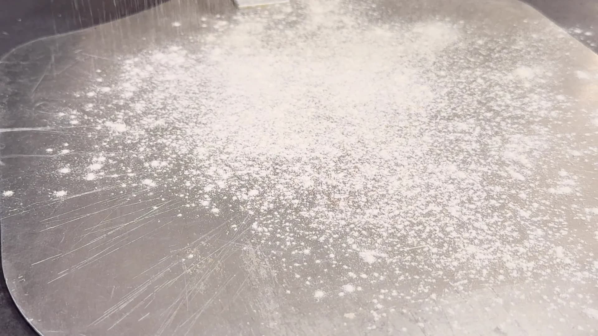 Rolled-out flammkuchen dough dusted with flour on a pizza peel.