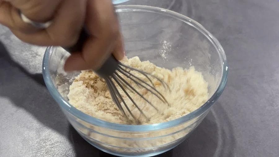Whisking dry ingredients together in a glass bowl for pumpkin spice cookie dough.