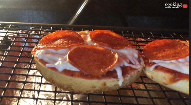 Pepperoni pizza bagels on a broiler rack with melted cheese and browned pepperoni slices.