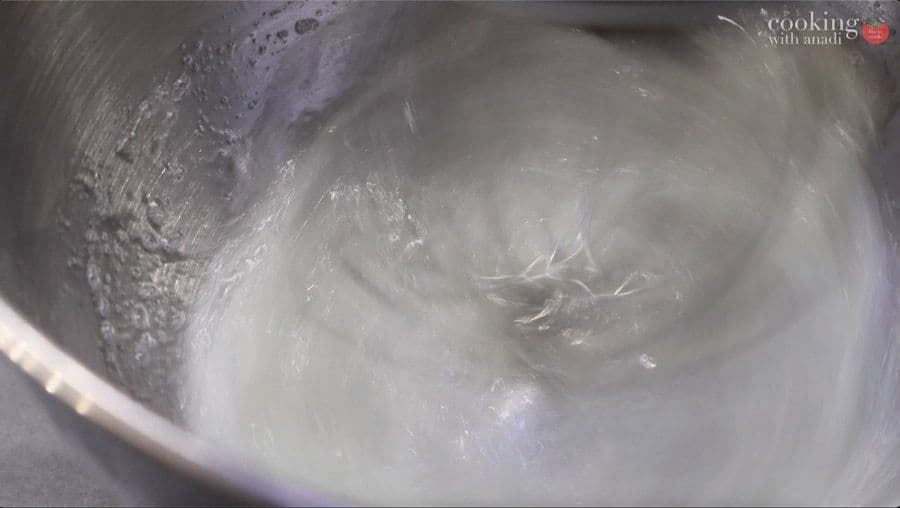 Whipped egg whites with soft peaks in a mixer bowl, ready to be folded into chocolate mousse.