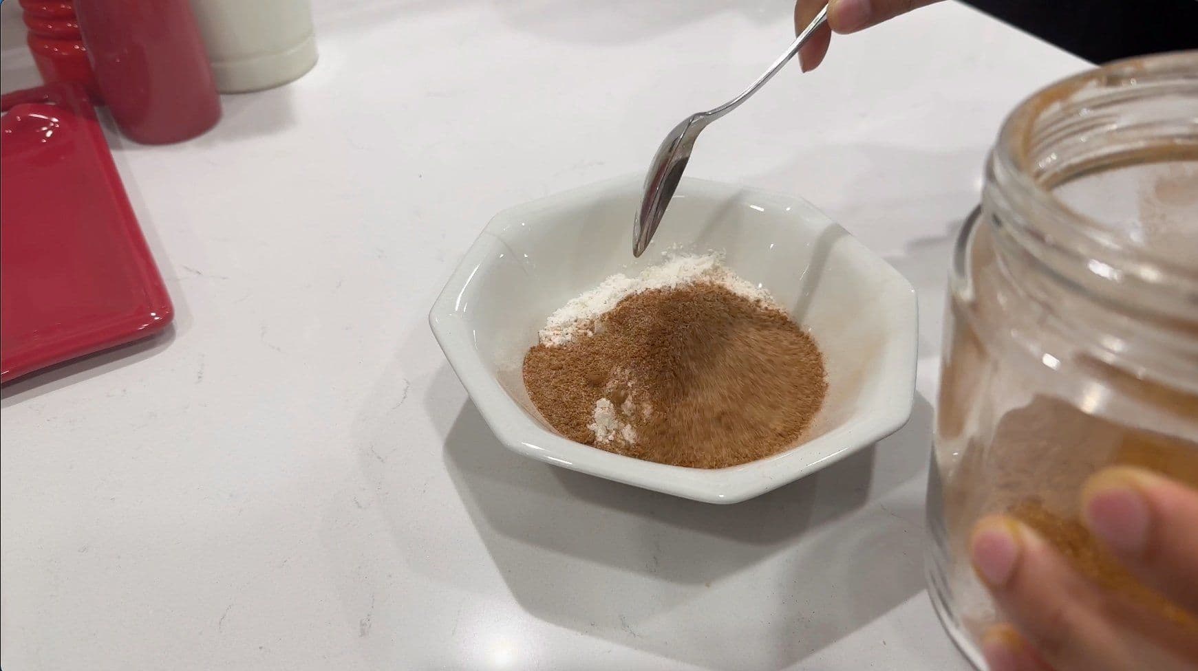 Cinnamon sugar mixture in a white bowl with a spoon, being prepared for overnight French toast casserole.