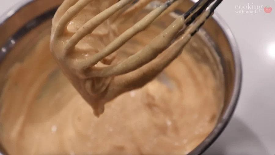 Whisk attachment lifting creamy pumpkin cream cheese filling from a bowl.