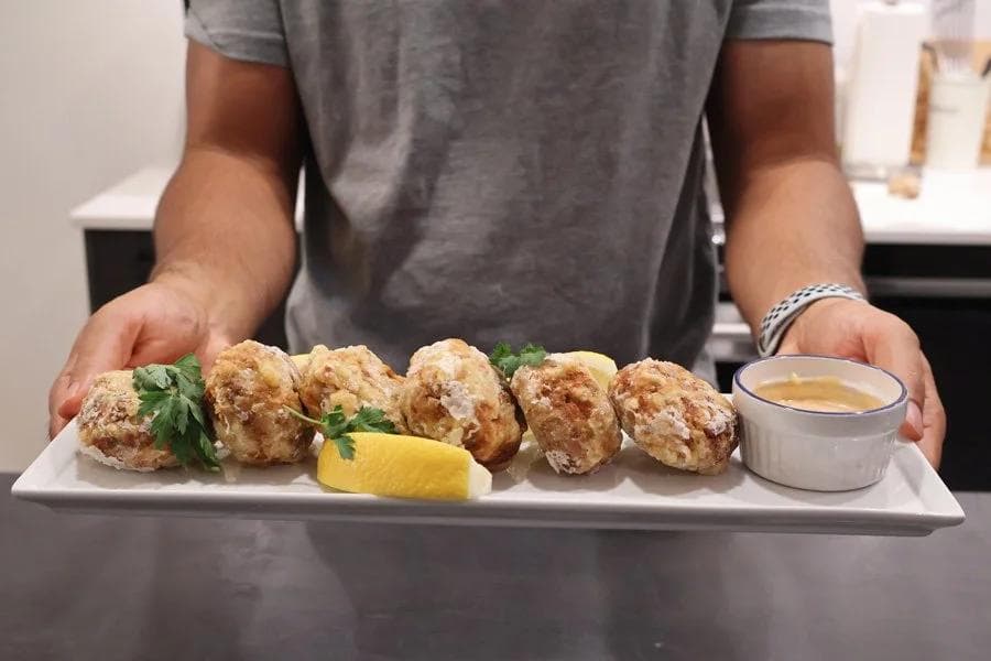 Plated perkedel daging kentang golden-brown potato fritters garnished with parsley, lemon wedge, and dipping sauce.