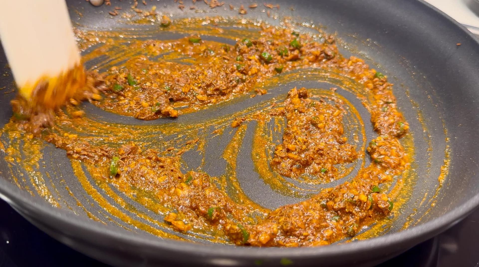 Spiced potato and pea filling being stirred in a pan with a wooden spoon, showing golden spices mixed with potato chunks.