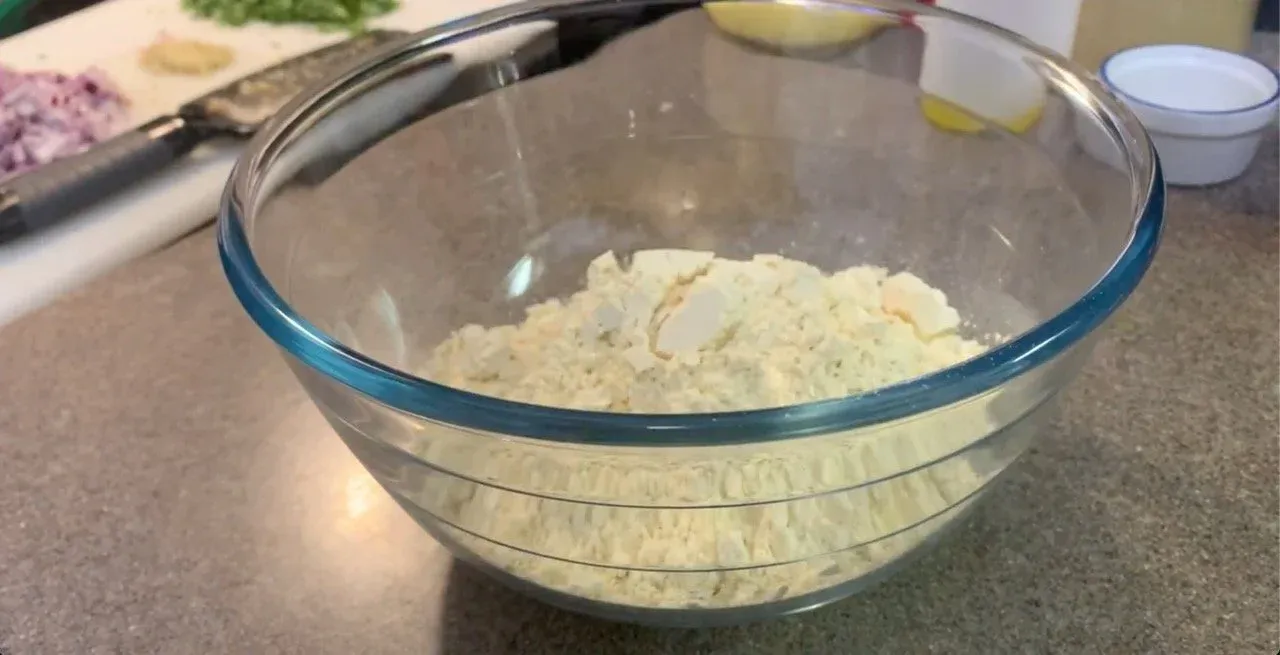 Dry besan flour and spices mixed together in a glass bowl before adding water.