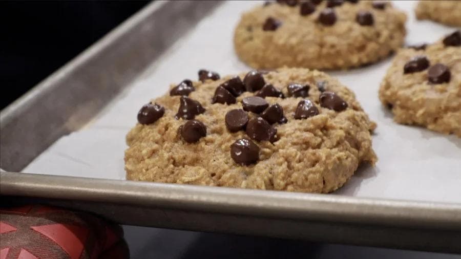 High protein pumpkin chocolate chip cookies cooling on a parchment-lined baking tray, slightly underbaked in the center.
