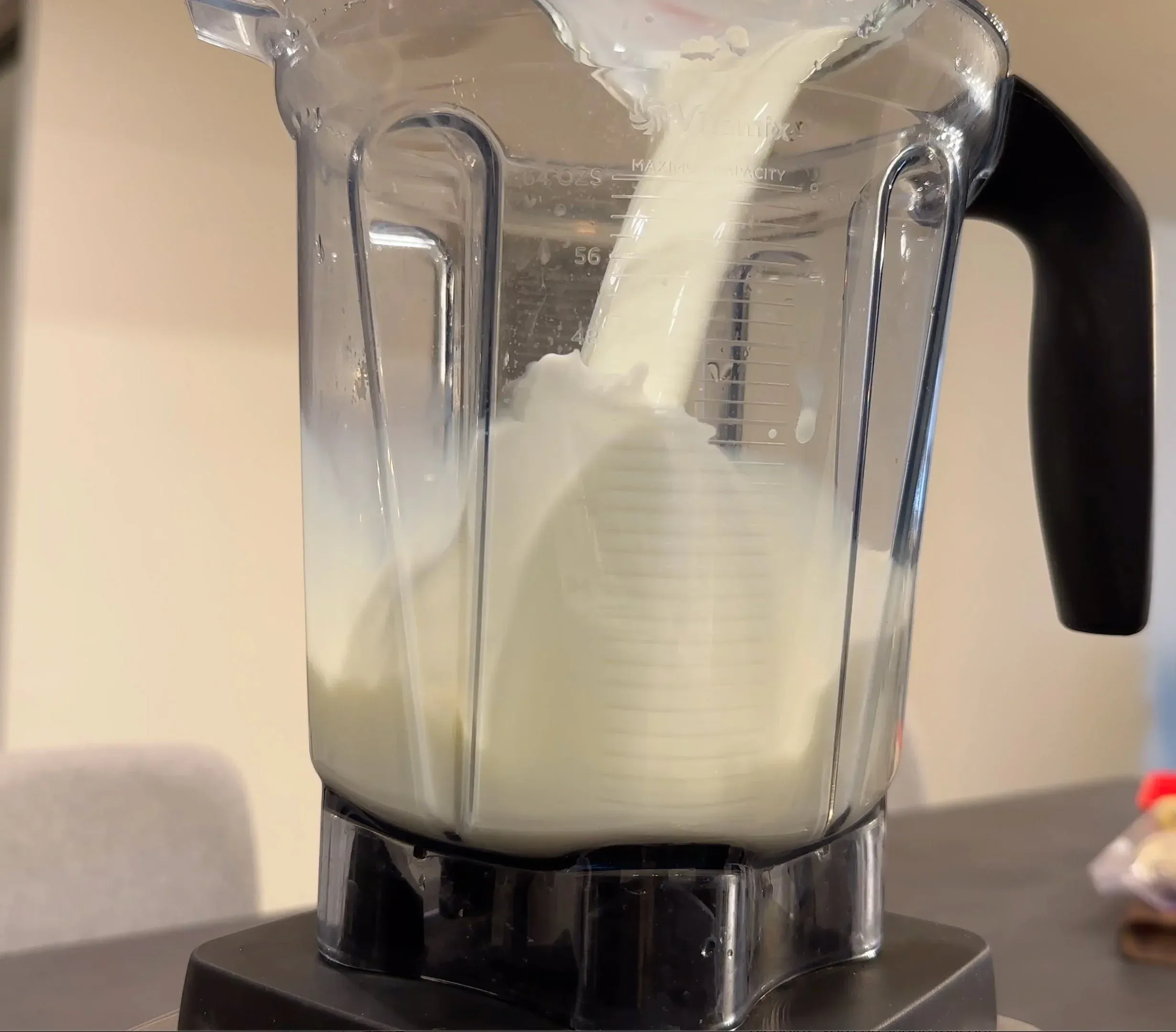 Blender pitcher filled with creamy white banana mocha frappe mixture being blended on high speed.