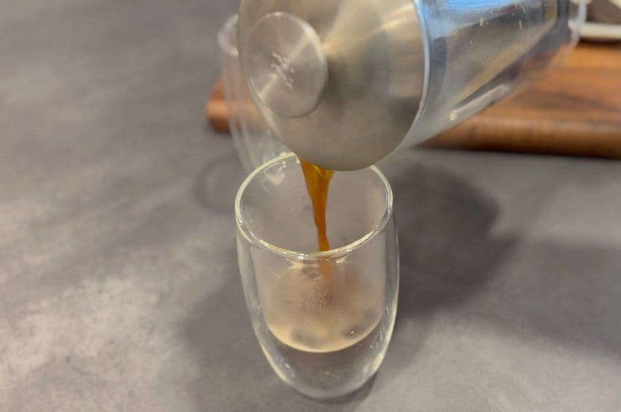 Strong espresso being poured into a glass cup during preparation of an Oreo latte.