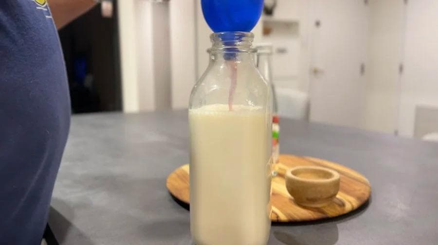 Gulabi doodh (Indian pink milk) in a clear glass bottle with a blue cap, ready to chill and serve.