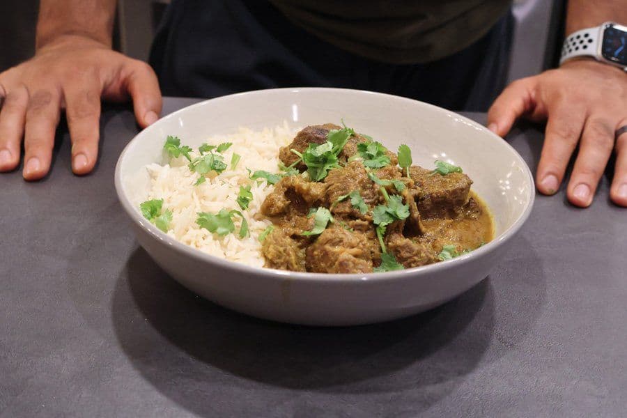 Balinese Beef Rendang served in a white bowl with white rice and garnished with fresh cilantro.