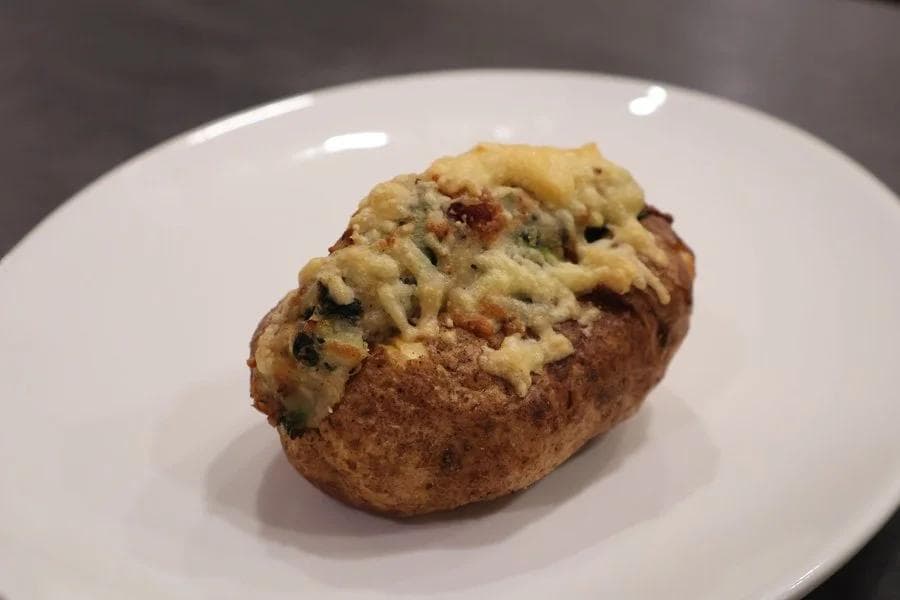 Twice baked potato topped with creamy filling on a white plate