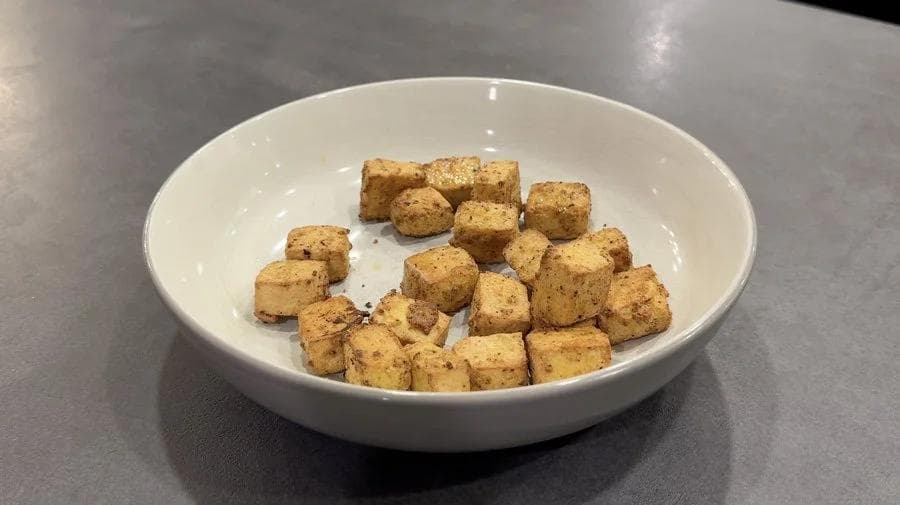 Crispy golden-brown tofu cubes in a white bowl, ready to be coated with sauce.
