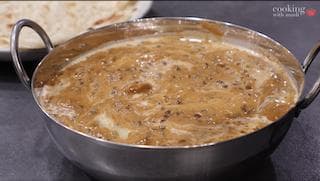 Creamy dal makhani simmering in a steel bowl, rich brown sauce with visible whole lentils and spices.