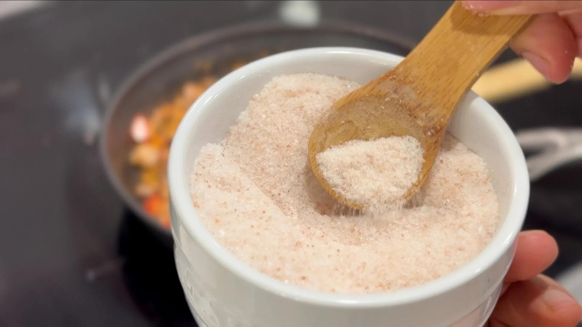 Wooden spoon holding garam masala powder over a white bowl filled with the spice mixture for mushroom patties.