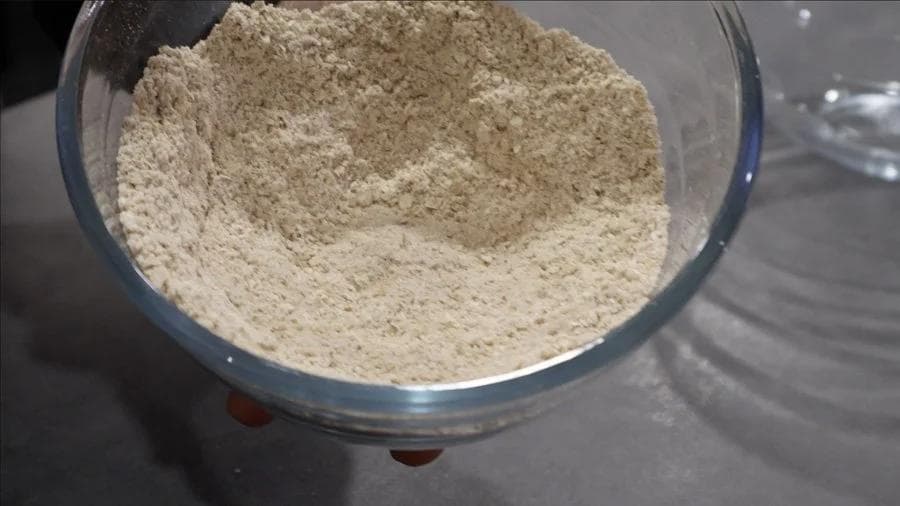 Dry ingredients mixed together in a glass bowl: oat flour, pumpkin spice, protein powder, baking powder, and salt.